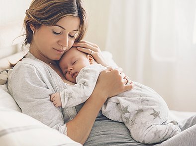 Mutter kuschelt mit schlafendem Baby