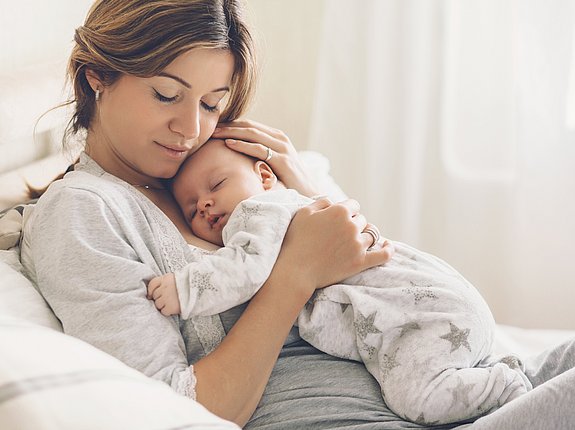 Mutter kuschelt mit schlafendem Baby