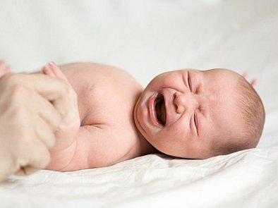 Schreiendes Baby liegt auf dem Rücken.