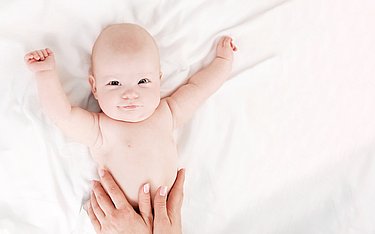 Mutter massiert sanft geblähten Baby-Bauch.