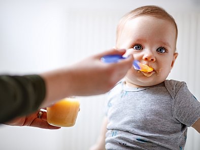 Glückliches Baby wird mit Brei gefüttert