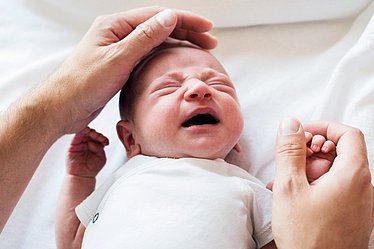 Schreiendes Baby wird zärtlich gestreichelt.