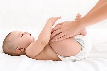 Baby mit Baby-Blähungen bekommt Osteopathie-Behandlung.