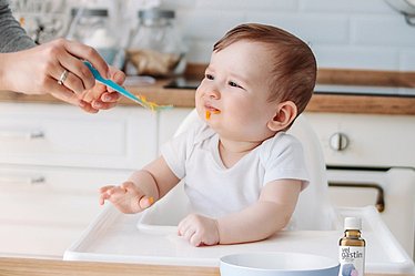 Baby wird mit Brei gefüttert.