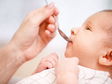 Mutter gibt Baby Medikament mit Löffel